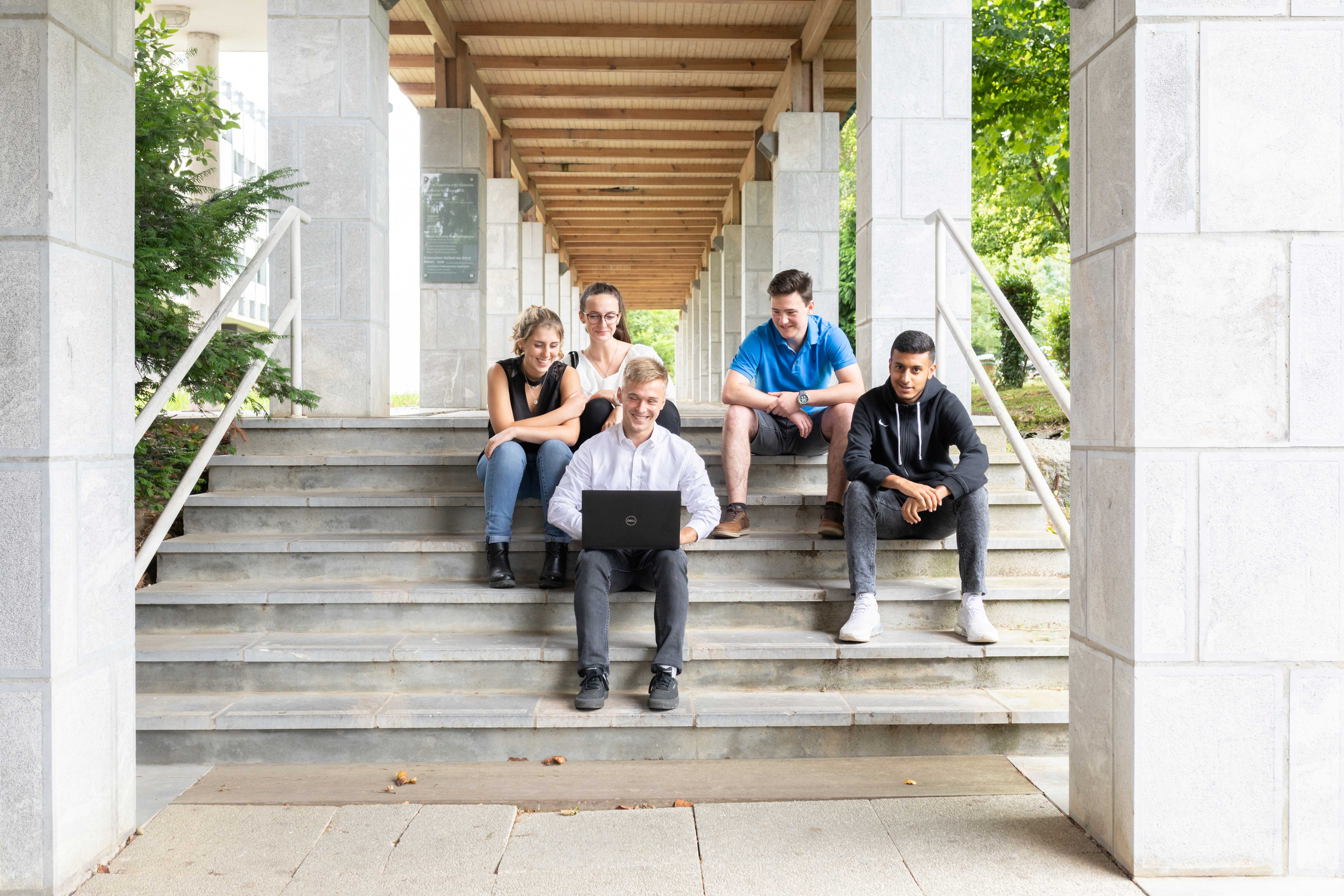 5 étudiants assis sur les marches à l'extérieur de l'IUT ANGLET